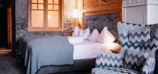 Peternhof Neue Zimmer/Suiten: Bett mit Wabenkopfhaupt, Fauteuil mit Zickzackmuster, Blumentapete